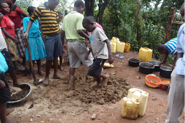 Students mix the clay for the bricks with their feet. Photo courtesy of Kasiisi Project / Camp Uganda.